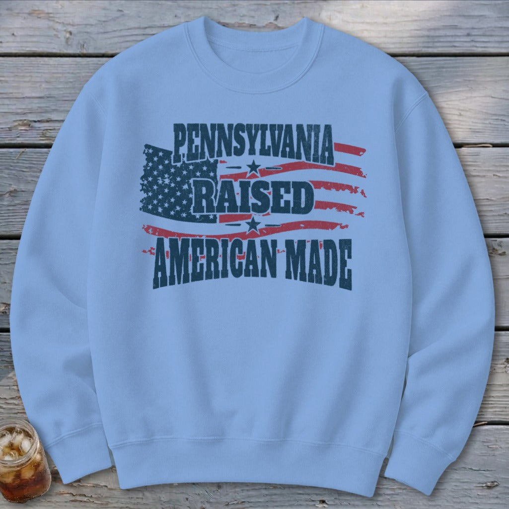 Light blue crewneck sweatshirt featuring a distressed American flag and the text Pennsylvania Raised American Made.