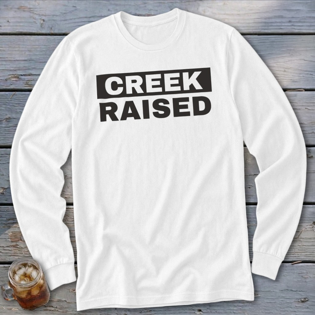 White long-sleeve shirt with black "CREEK RAISED" text across the chest.