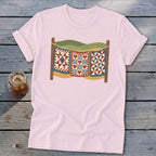 A light pink t-shirt with a vintage graphic of three quilts hanging on a clothesline.