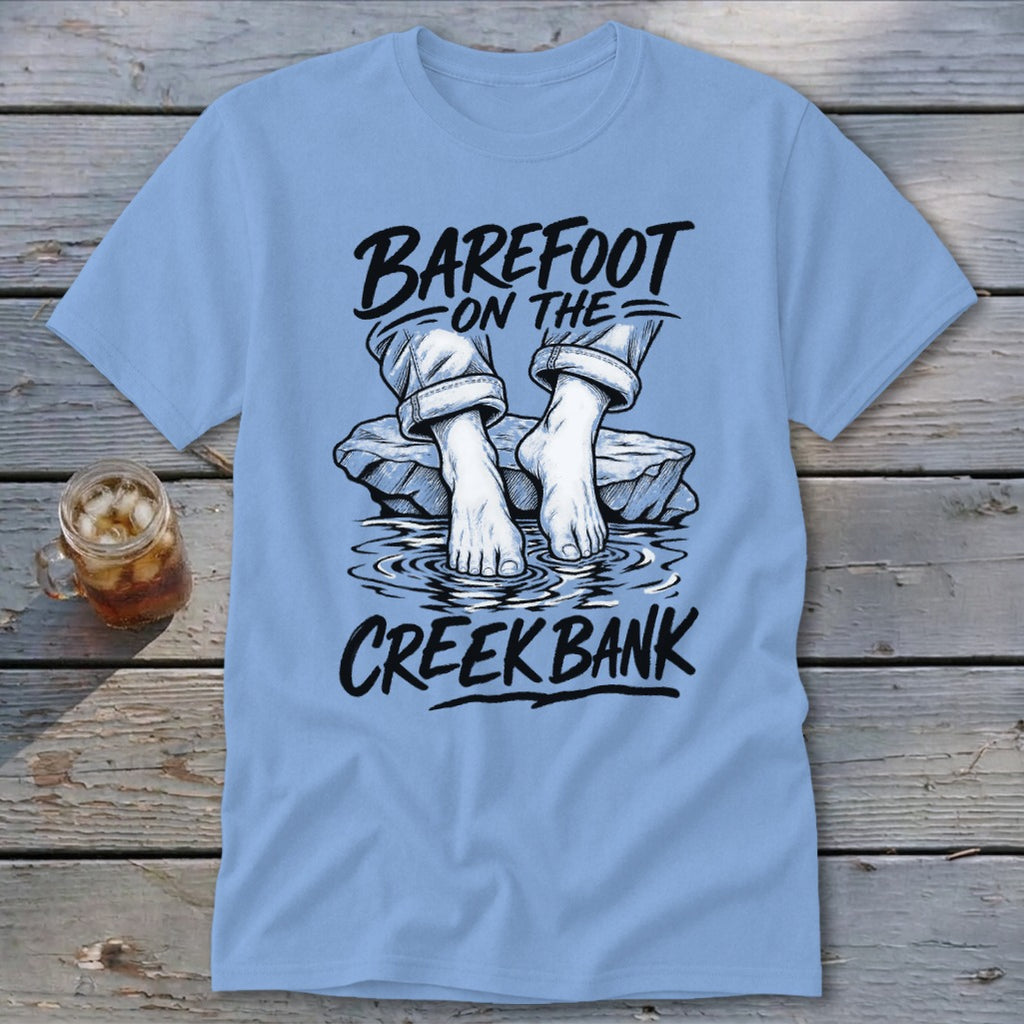 Light blue t-shirt graphic with text "Barefoot on the Creek Bank" and bare feet in water.