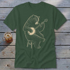 Green t-shirt with a drawing of a bear sitting on a stool playing a banjo.