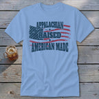 Light blue t-shirt with "Appalachian Raised American Made" in distressed navy print over an American flag.