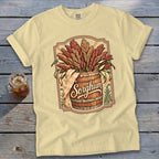 Pale yellow t-shirt with a graphic of sorghum stalks in a wooden barrel labeled "Sorghum."