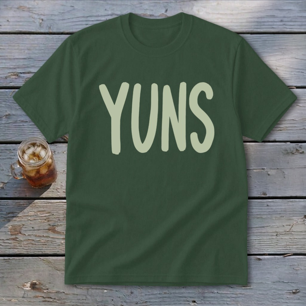 Dark green t-shirt with "YUNS" in light green font on a wooden surface.