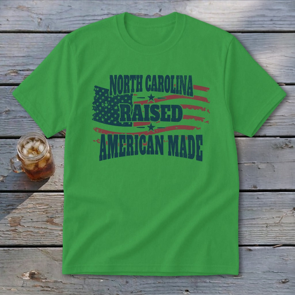 Green t-shirt with distressed American flag graphic and text reading North Carolina Raised American Made.