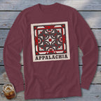Maroon long-sleeve t-shirt with a square Appalachian quilt block graphic and text on a wooden background.