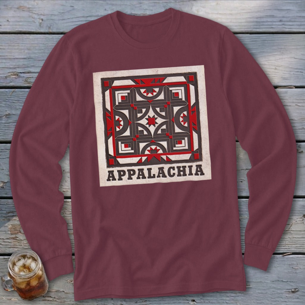 Maroon long-sleeve t-shirt with a square Appalachian quilt block graphic and text on a wooden background.