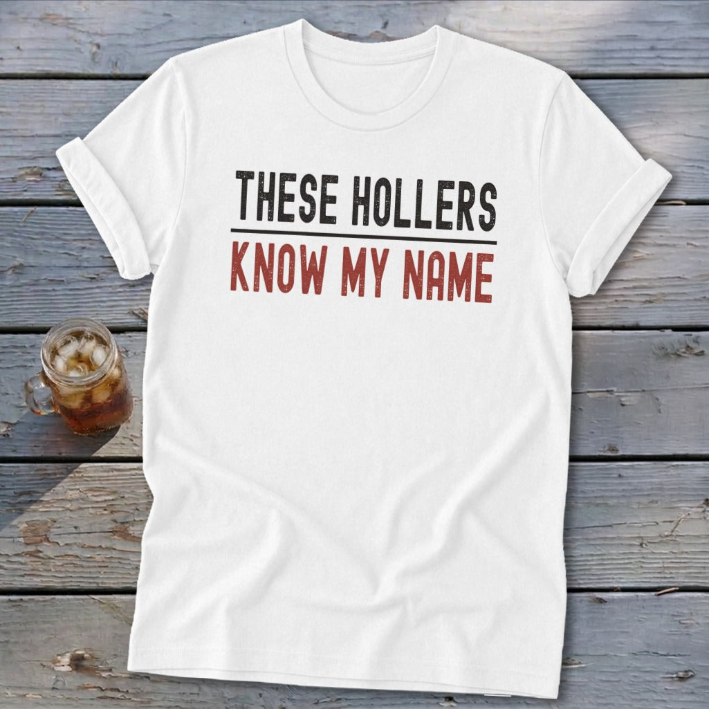 White t-shirt with text "THESE HOLLERS KNOW MY NAME" in black and red.