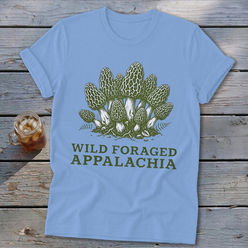 Light blue t-shirt with green morel mushroom illustration and "WILD FORAGED APPALACHIA" text.