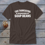 A brown crewneck t-shirt with white text reading THIS THANKSGIVING IS SPONSORED BY SOUP BEANS.