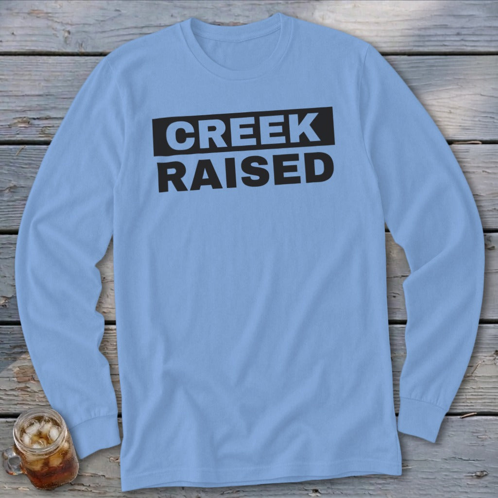 Light blue long sleeve shirt with black text that reads "CREEK RAISED".