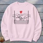 Pink sweatshirt with a minimalist drawing of a couple and dog on a swing.