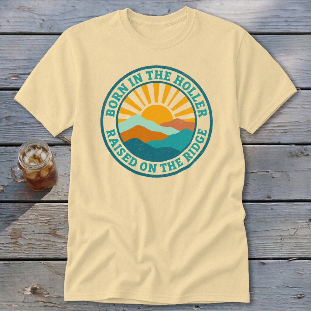 Cream-colored crewneck t-shirt featuring a retro circular graphic with mountains, a rising sun, and text.