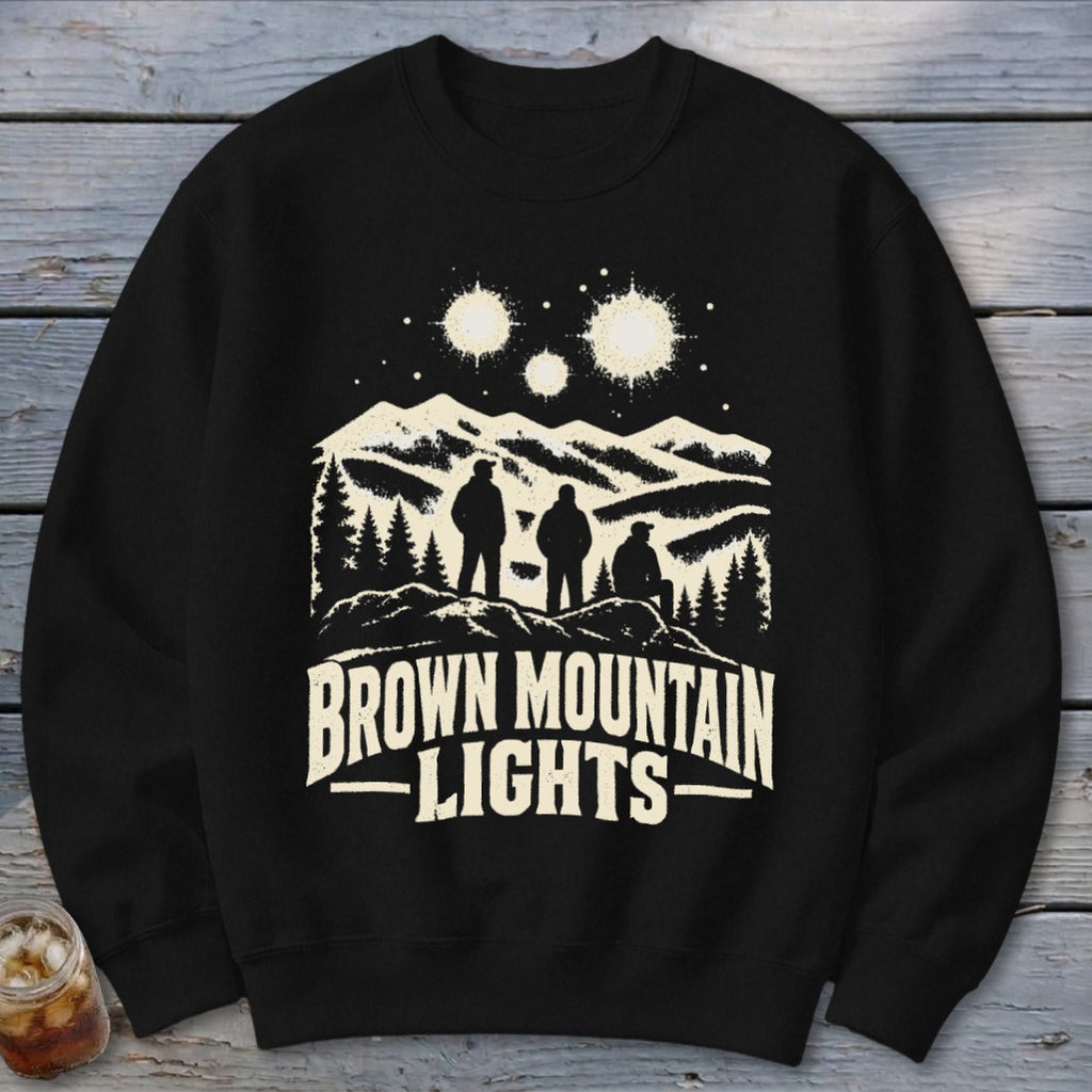 A black crewneck sweatshirt printed with a graphic of three figures looking at mountain lights.