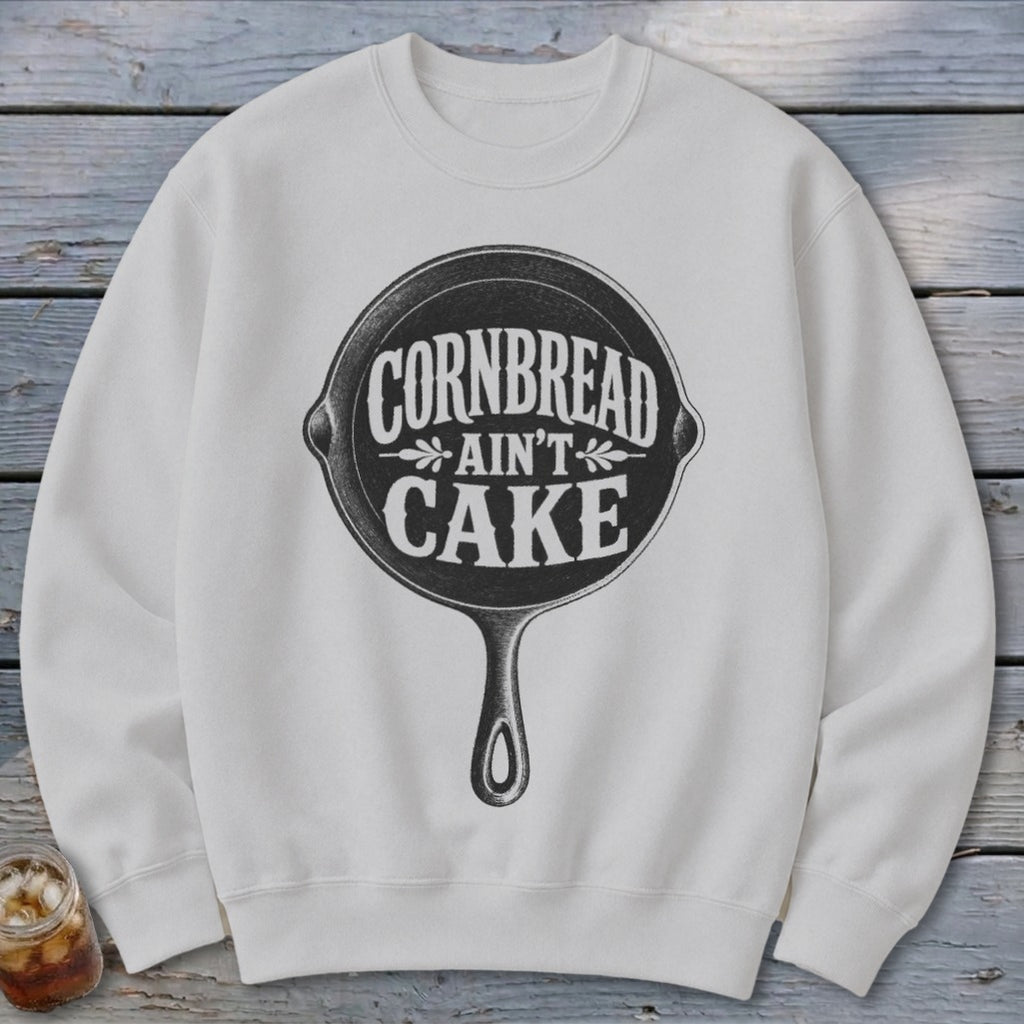 White sweatshirt with black graphic of cast iron skillet reading "Cornbread Ain't Cake."