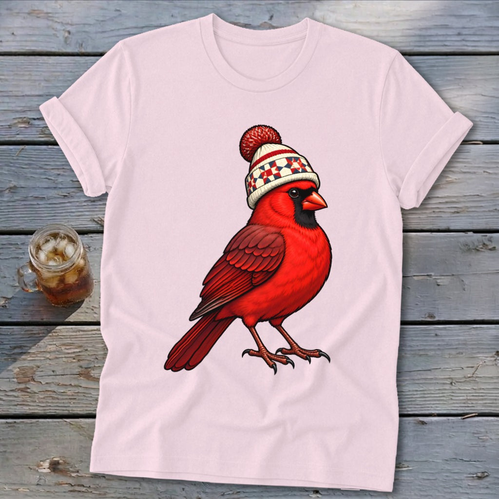 Light pink short-sleeved t-shirt featuring a graphic of a bright red cardinal wearing a winter hat.