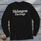 Black long-sleeve t-shirt with white serif text reading "Melungeon Heritage" on a wooden background.