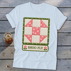 White t-shirt with a quilt design featuring a "Shoo Fly" block and text.