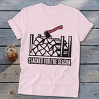 Pink t-shirt with black graphic of firewood, an axe, and text "STACKED FOR THE SEASON".