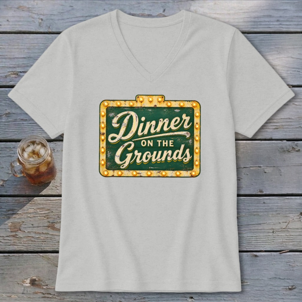 Light gray V-neck t-shirt featuring a green marquee sign graphic with the text Dinner on the Grounds.