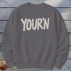 Gray sweatshirt with "YOUR'N" printed in cream, soft, rounded font.