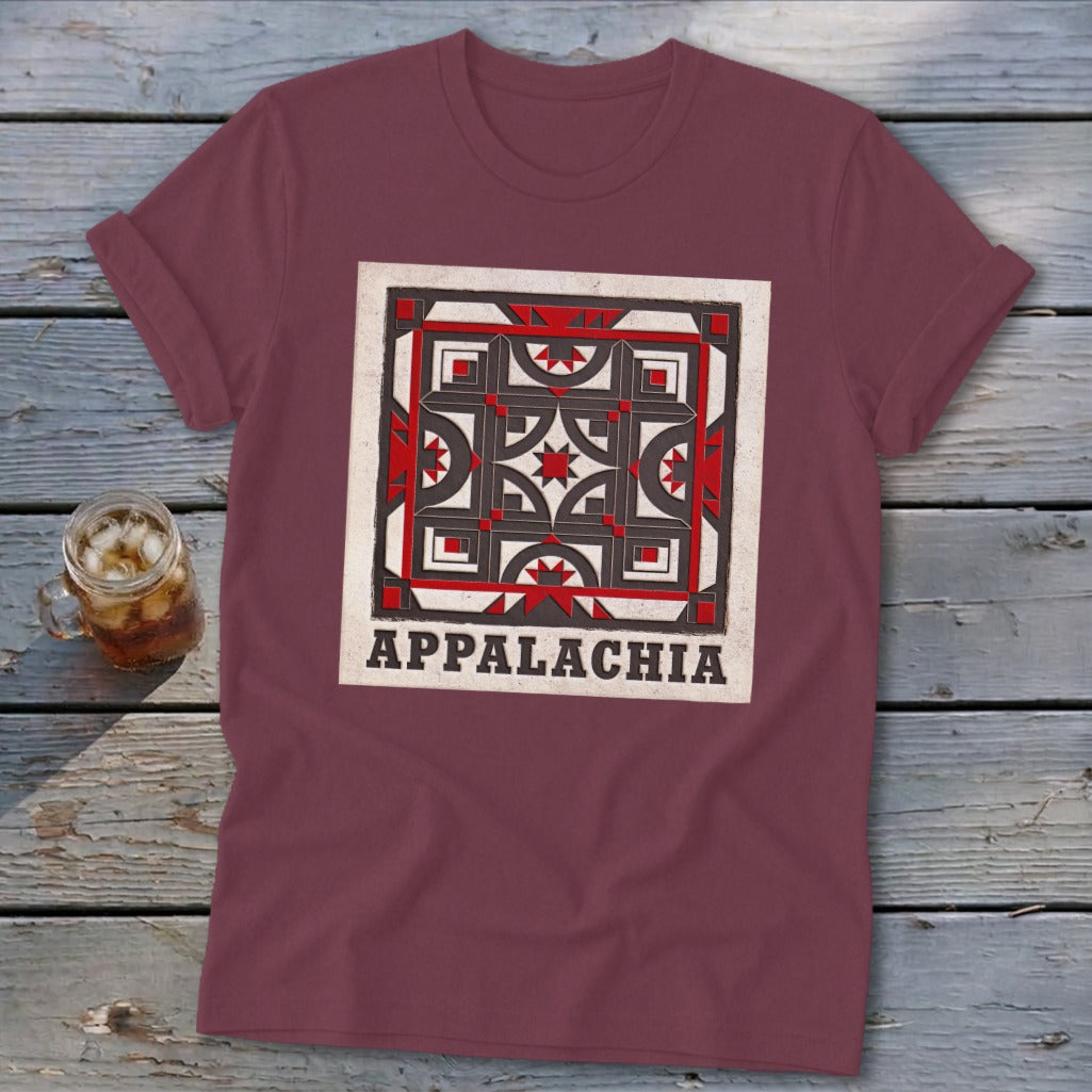 Maroon t-shirt featuring a quilt block graphic and the text Appalachia, lying on a wooden surface.