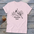 Light pink t-shirt with a black line drawing of a cardinal on a branch with flowers and "Mountain Soul" text.