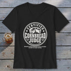 Black V-neck t-shirt featuring a white round graphic with text reading Certified Cornbread Judge.