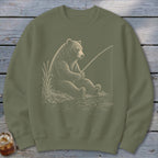 Bear sitting by the water, holding a fishing rod.