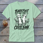 Light green t-shirt with "Barefoot on the Crick Bank" text and illustration.