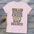 Light pink t-shirt featuring stacked retro text in green, brown, blue, yellow, and grey.