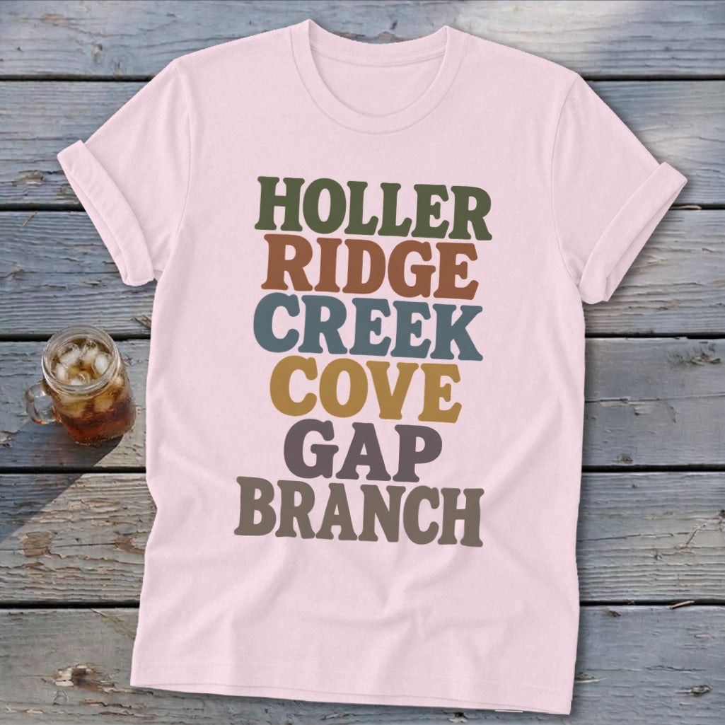 Light pink t-shirt featuring stacked retro text in green, brown, blue, yellow, and grey.