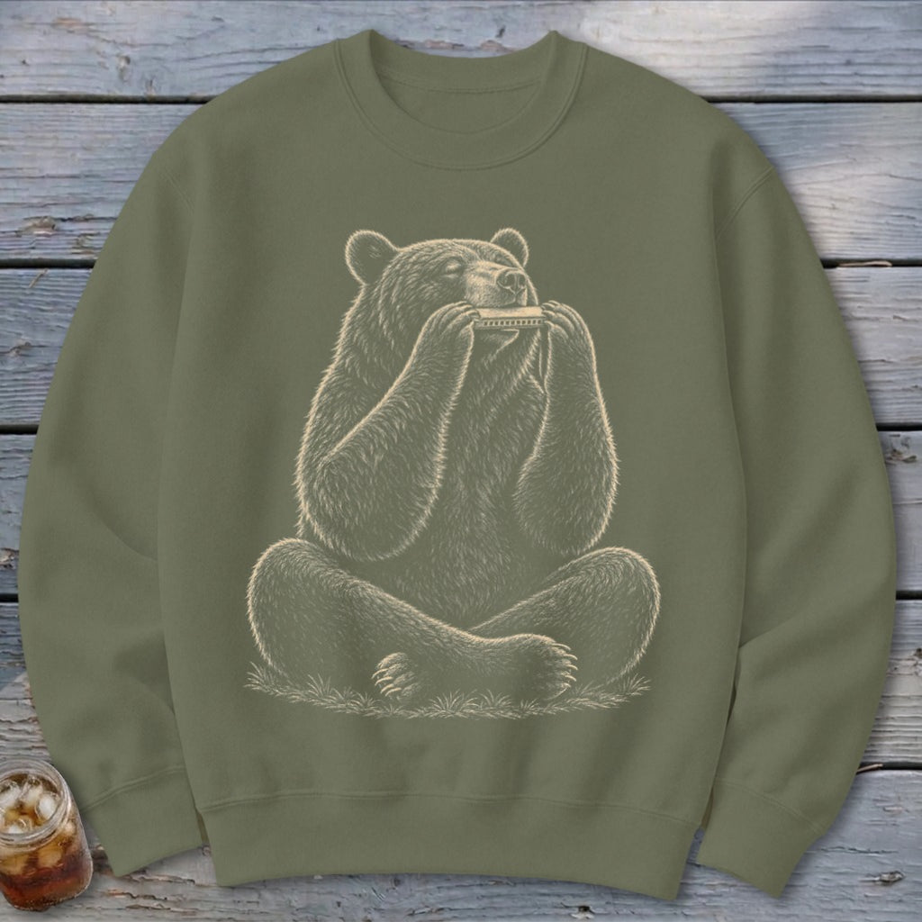 Bear sitting cross-legged and playing a harmonica on a green sweatshirt.