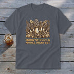 A dark gray t-shirt featuring a yellow graphic of morel mushrooms, leaves, and text reading MOUNTAIN GOLD MOREL HARVEST.