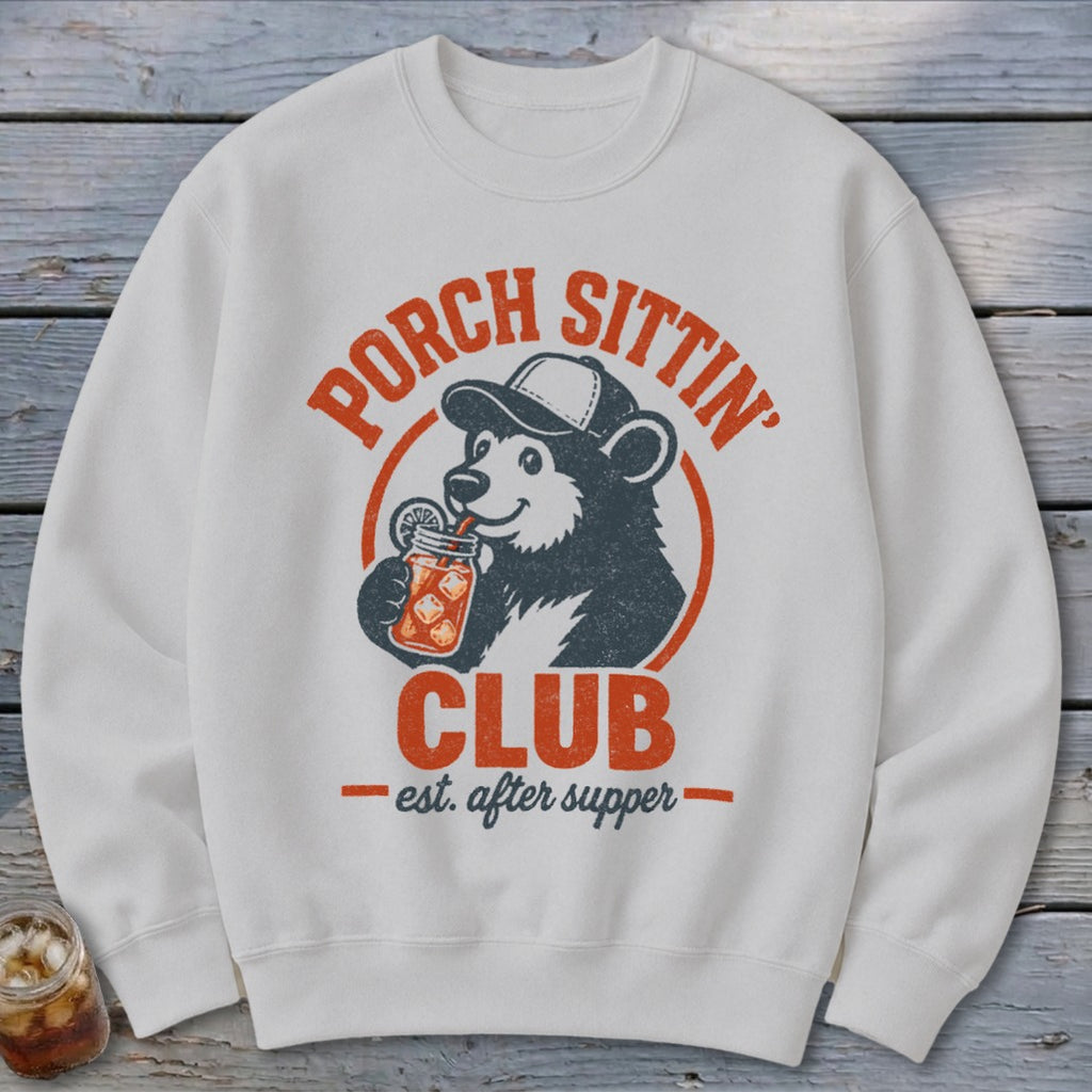 White sweatshirt with a bear drinking from a jar, text reads "Porch Sittin' Club est. after supper".