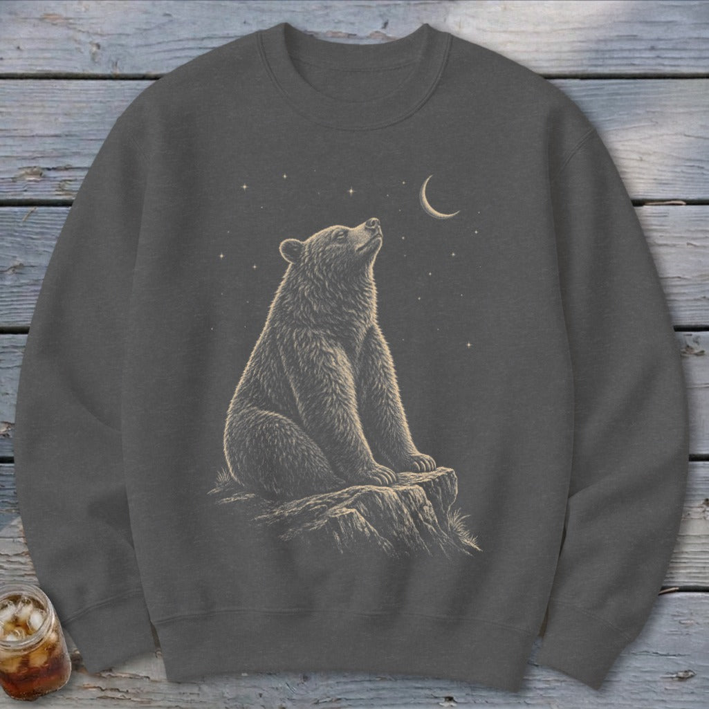Dark gray sweatshirt with a bear sitting on a rock looking at a crescent moon and stars.