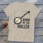 Tan t-shirt with banjo graphic and text "BORN IN THE HOLLER".