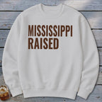 White sweatshirt with brown text reading "MISSISSIPPI RAISED".