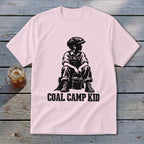 Pink t-shirt with black graphic of a boy in overalls and cap holding a bucket, text Coal Camp Kid.