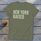 Olive green t-shirt with "NEW YORK RAISED" text in light beige.