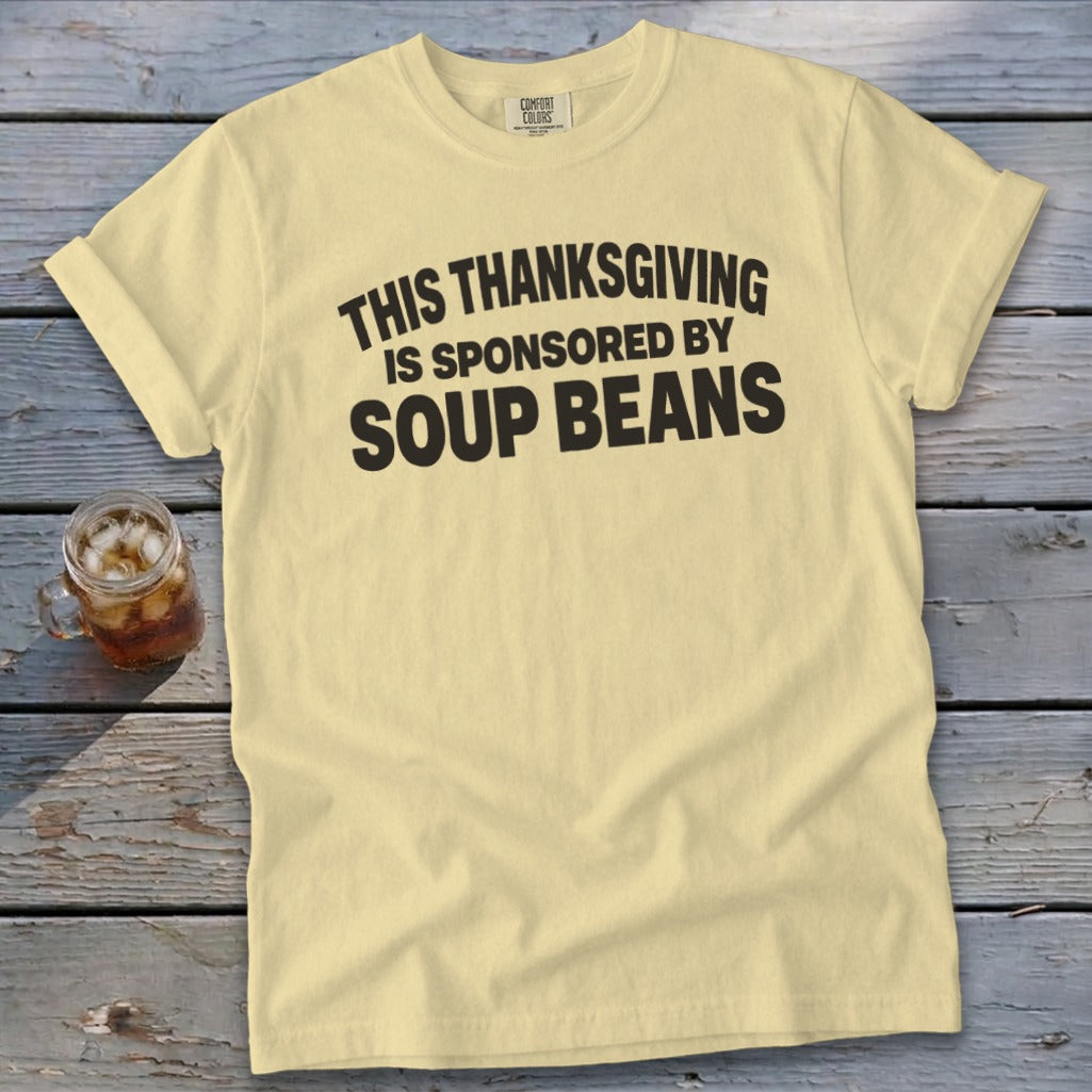 A light yellow t-shirt with black text that reads, "This Thanksgiving is sponsored by soup beans."