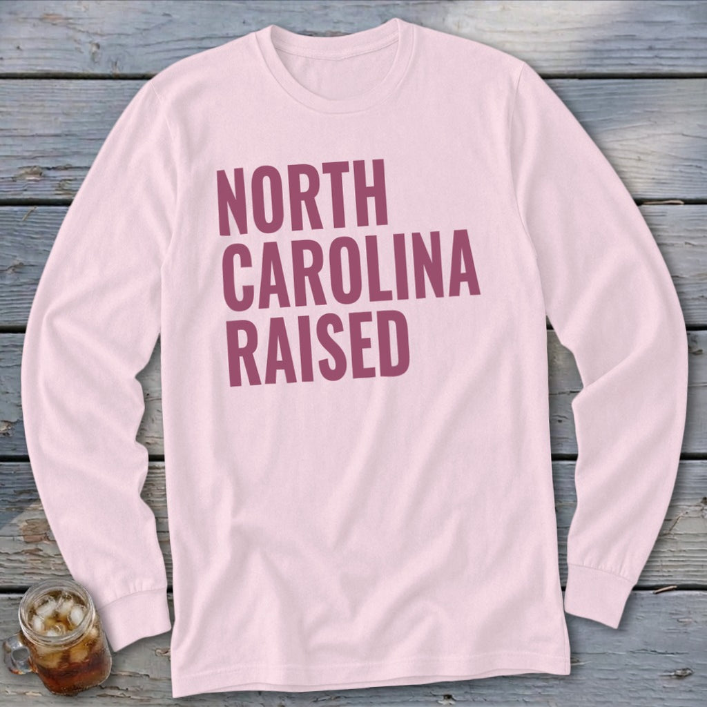Light pink long-sleeve shirt with "NORTH CAROLINA RAISED" text in maroon.
