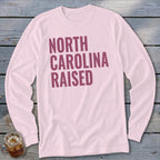 Light pink long-sleeve shirt with "NORTH CAROLINA RAISED" text in maroon.