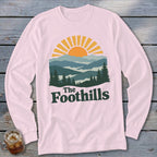 Light pink long-sleeve shirt with "The Foothills" graphic of mountains and sunrise.
