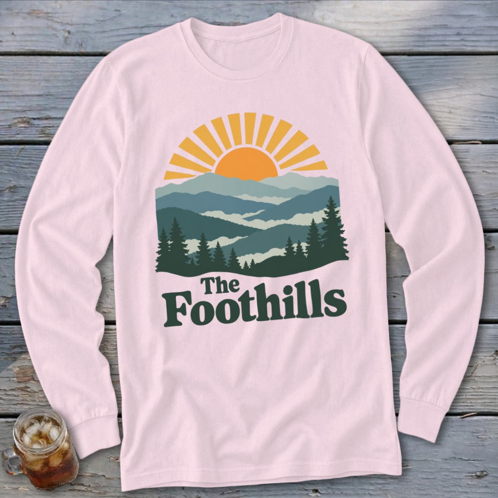 Light pink long-sleeve shirt with "The Foothills" graphic of mountains and sunrise.