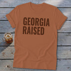 Orange t-shirt with "GEORGIA RAISED" in dark brown text.