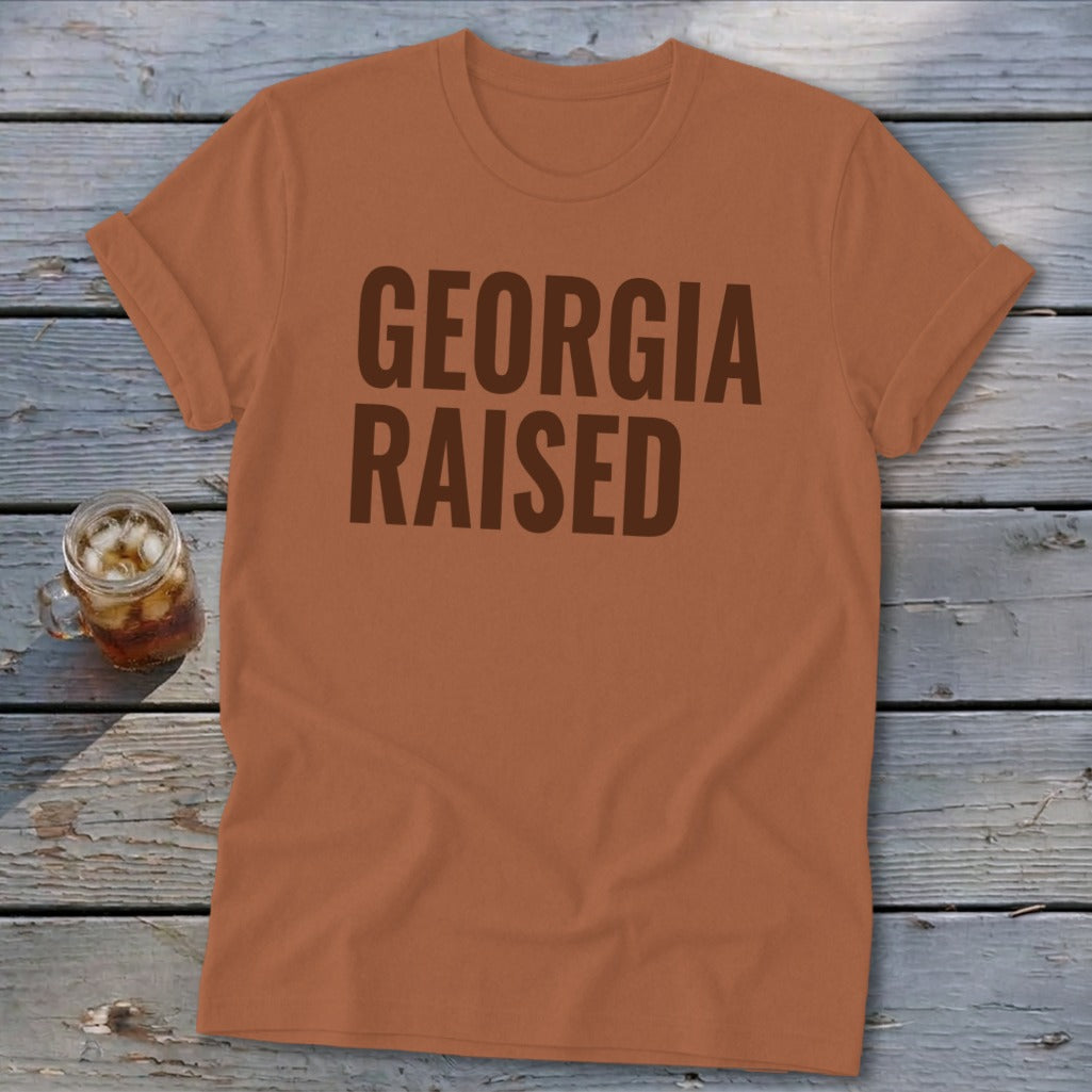Orange t-shirt with "GEORGIA RAISED" in dark brown text.