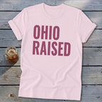 Pink t-shirt with large purple text reading "OHIO RAISED".