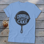 Light blue t-shirt with a graphic of a cast iron skillet that reads "Cornbread Ain't Cake".