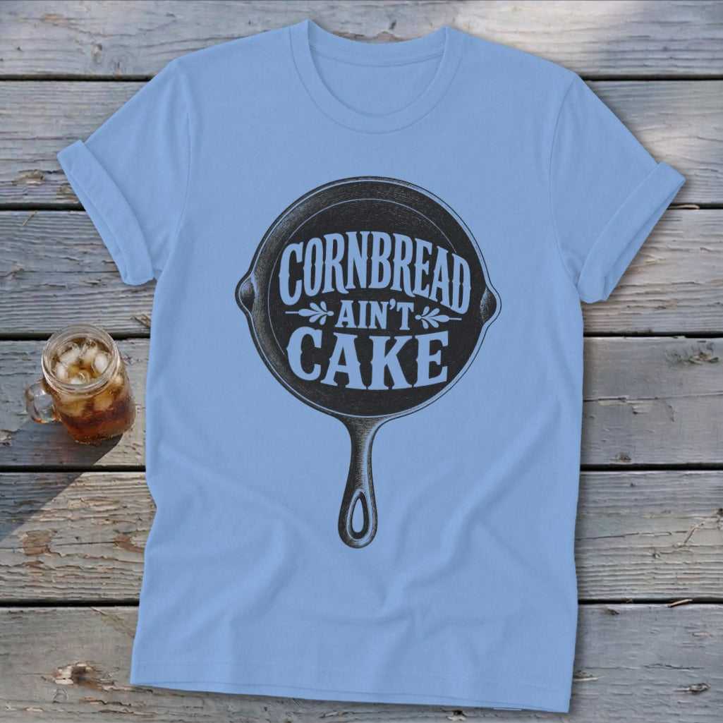 Light blue t-shirt with a graphic of a cast iron skillet that reads "Cornbread Ain't Cake".